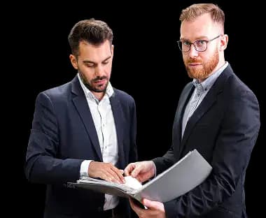 Two business professionals in formal attire reviewing paperwork together, one holding a folder and the other checking documents, demonstrating a careful and compliant business dissolution process.