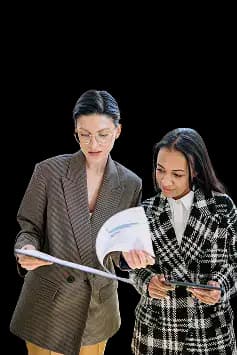 Two business professionals standing together, one reviewing paperwork and the other holding a tablet and looking at the documents, illustrating collaborative planning and document review for starting a nonprofit organization.
